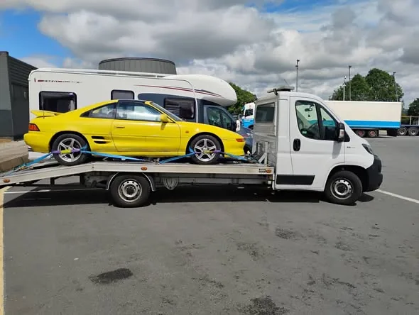 Bright yellow Toyota MR2 project car loaded on the transporter