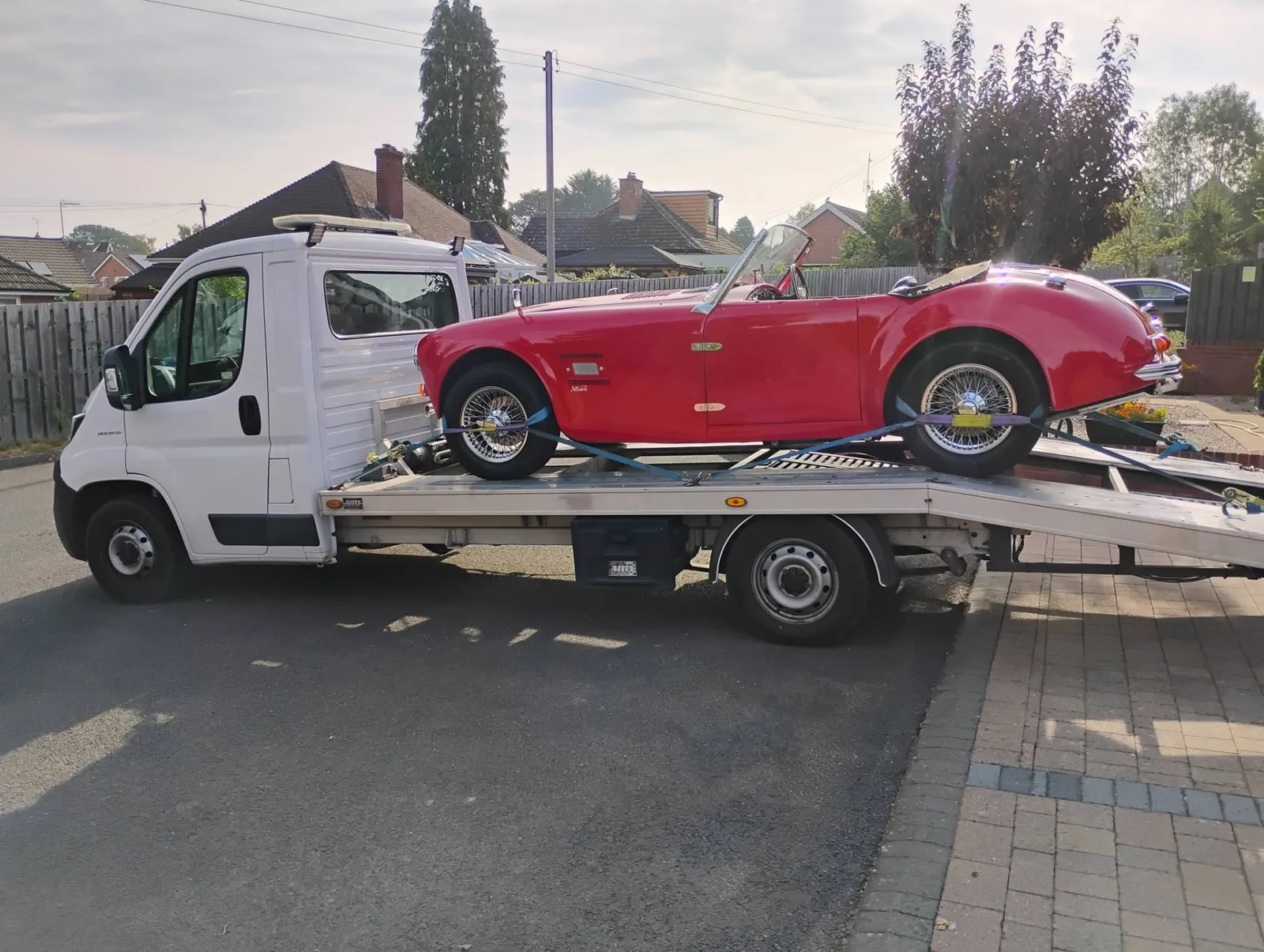 Red Allard roadster with wire wheels loaded on the transporter